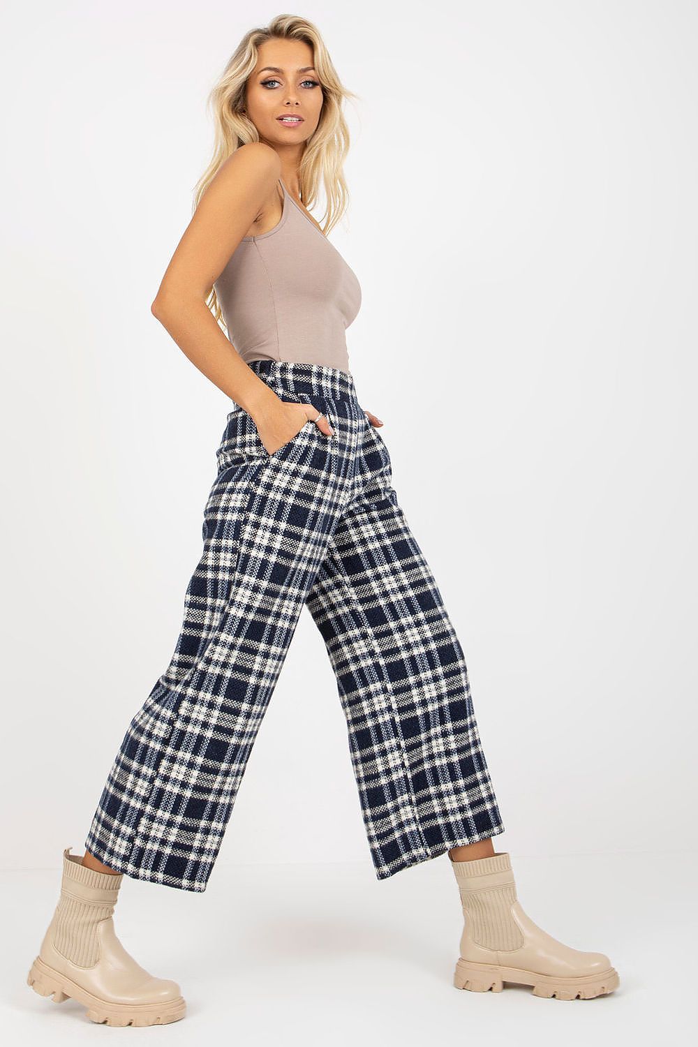 Sophisticated side profile of a woman wearing checkered wool trousers and a beige top, elegantly revealing the slip pockets and tailored fit.