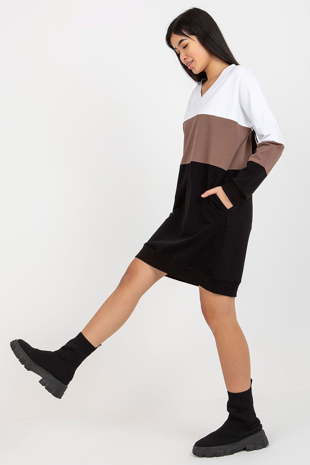Chic model showcasing a Rue Paris tracksuit dress with a flattering v-neckline. The dress, adorned with long sleeves and stylish colourblocking, is paired with trendy black ankle boots for a modern look.