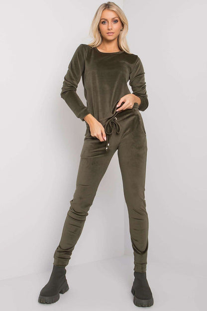 Elegant model presenting an olive green velour blouse and pants set by Rue Paris, designed with a tie waist and slip pockets.