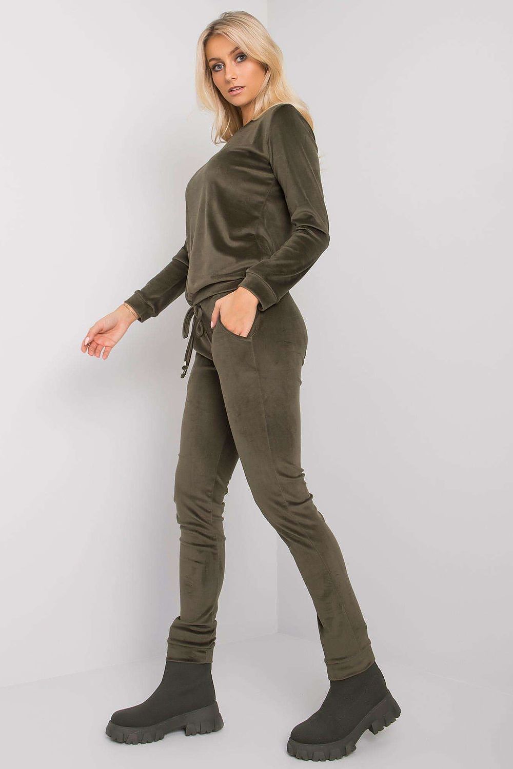 Elegant woman showcasing a luxurious velour blouse and pants set in rich olive green, featuring long sleeves, a round neckline, and stylish slip pockets, perfect for casual chic looks.