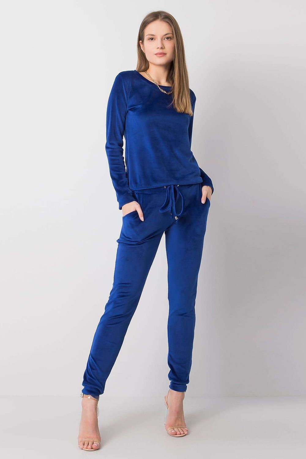 Sophisticated woman wearing a luxurious blue velour blouse and pants outfit, accentuated with a tie waist and trendy slip pockets, epitomising elegance and comfort.