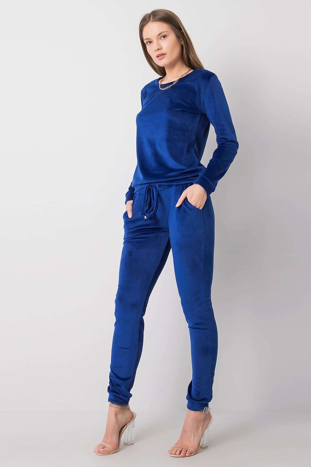 Elegant woman showcasing a luxurious blue velour blouse and pants set, featuring a round neckline and tie-waist. Perfect for sophisticated leisurewear.
