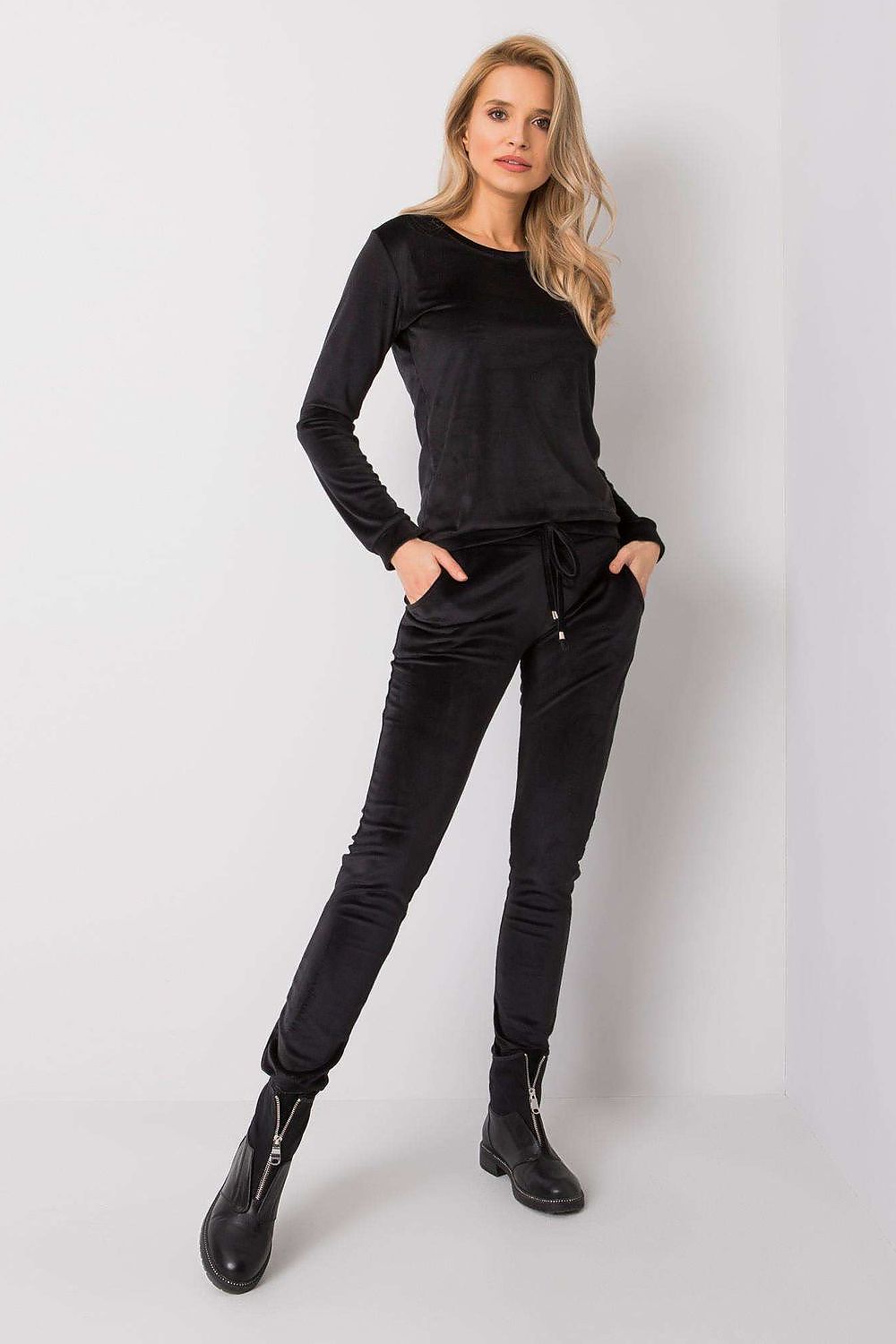 Chic woman modelling a classic black velour blouse and pants set, enriched with long sleeves and a comfortable tie waist for elevated elegance.