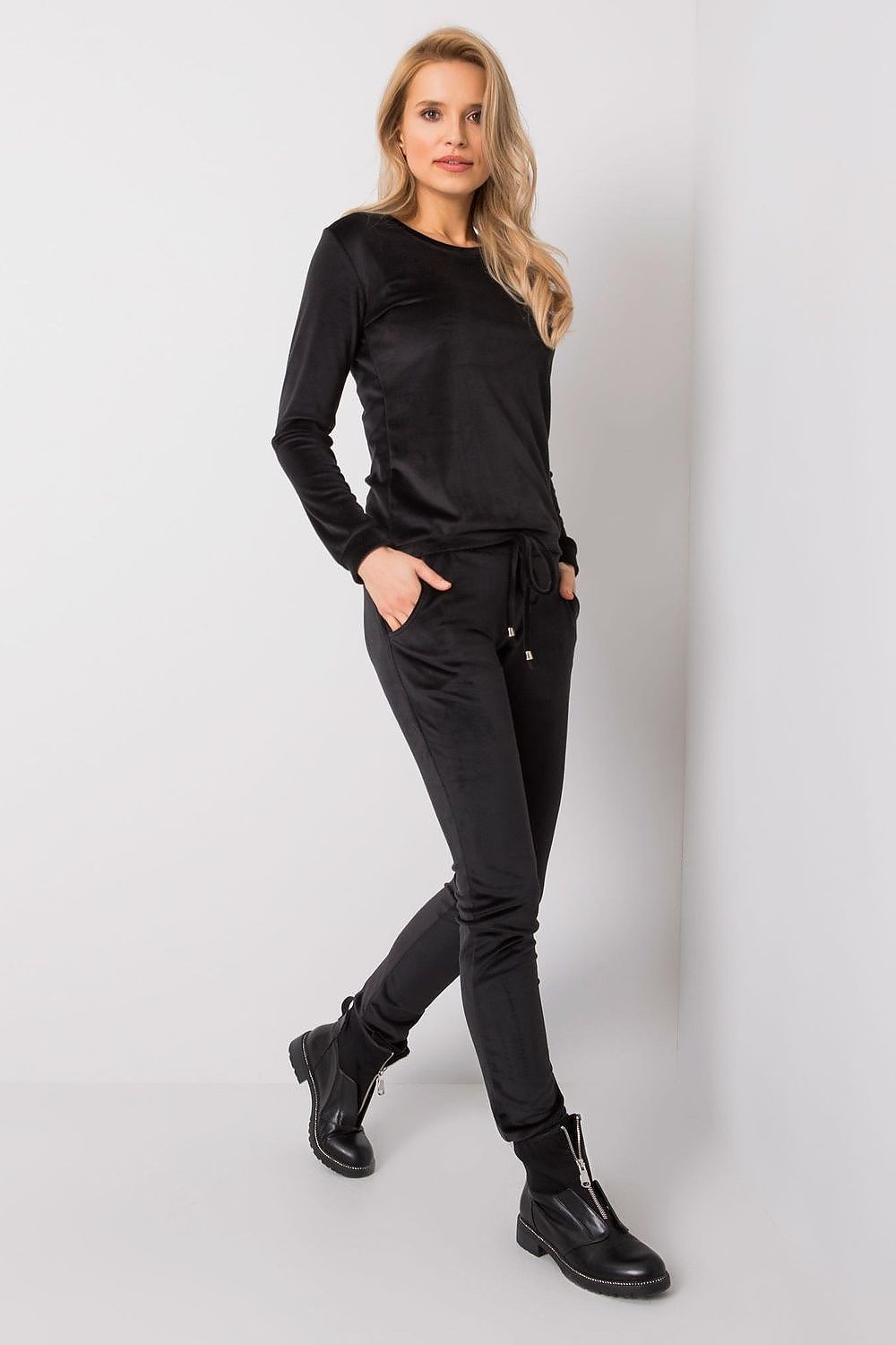 Sophisticated side view of a lady in a black velour outfit, featuring stylish lounge pants and a blouse for a luxurious casual look.