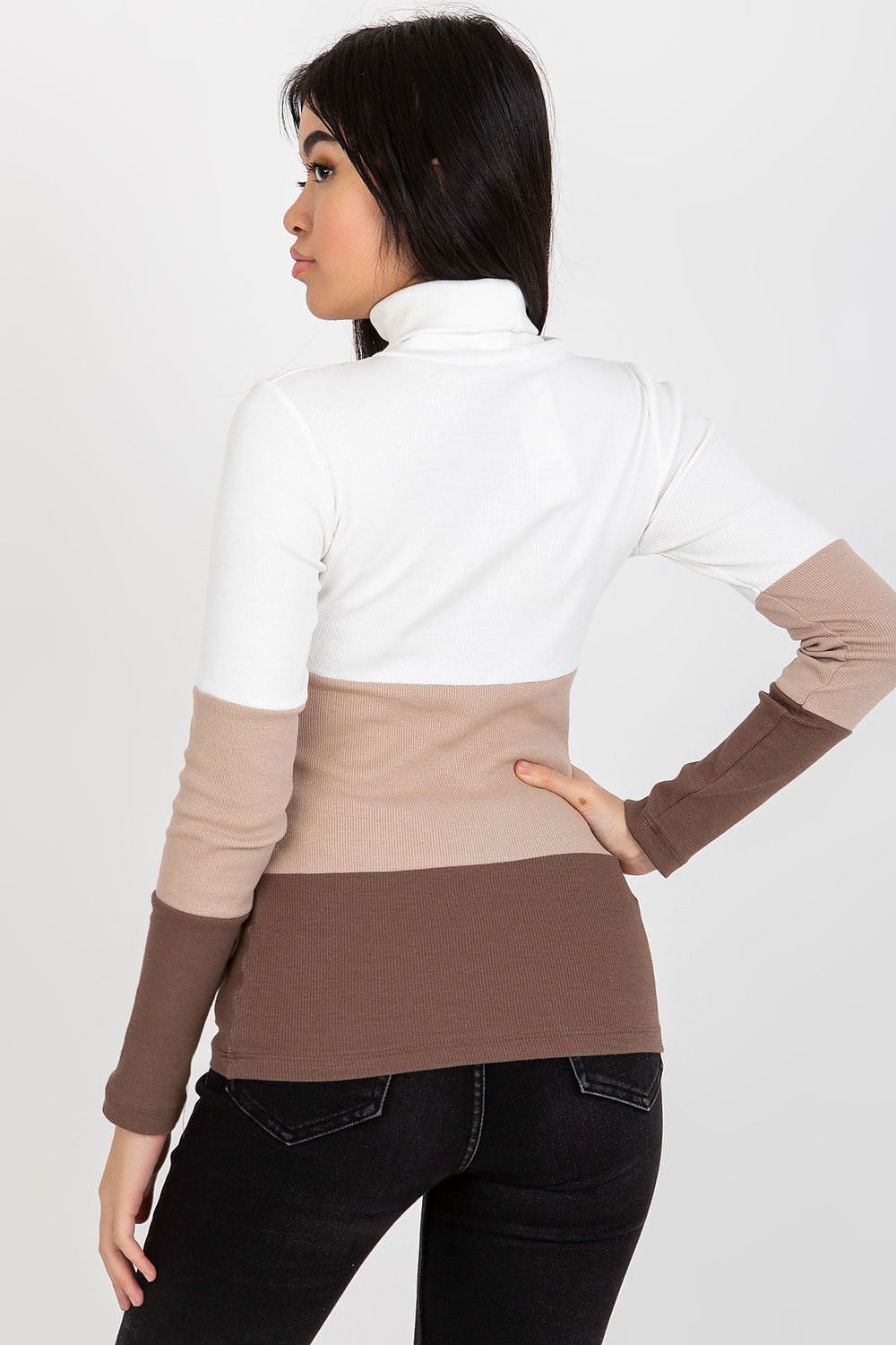 Back view of model wearing a luxurious ribbed turtleneck sweater in cream, brown, and beige, showcasing the elegant colour blocking.
