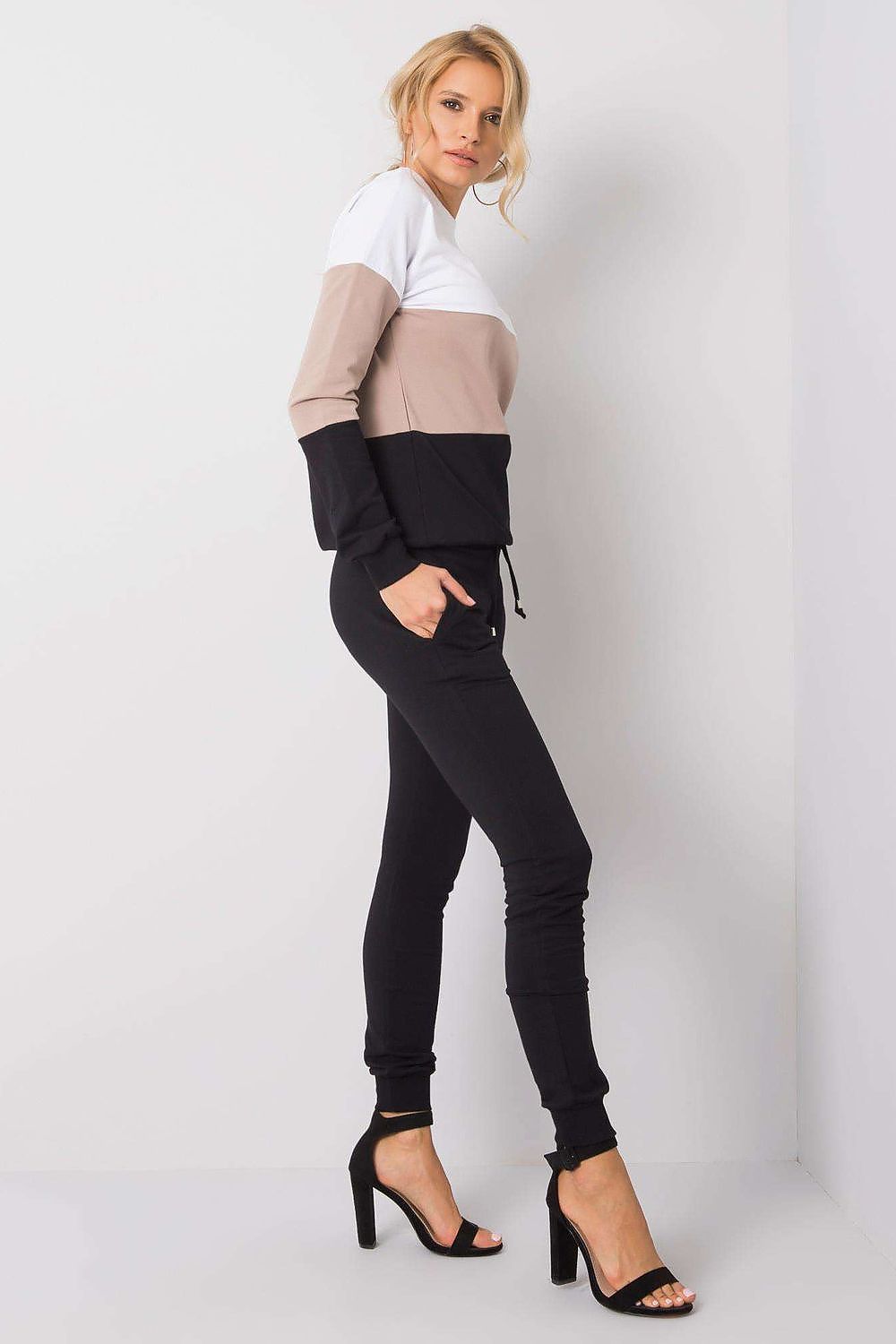 Side view of a model in a premium 2-piece ensemble by Rue Paris. The stylish cotton sweatshirt with contrasting colour blocks complements the sleek black jogger pants for a refined casual look.