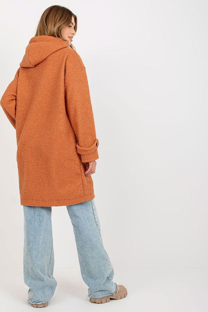 Back view of a woman wearing a luxurious long sleeve plush coat in warm orange with a hood, featuring a cozy unlined design, paired with loose-fitting jeans.