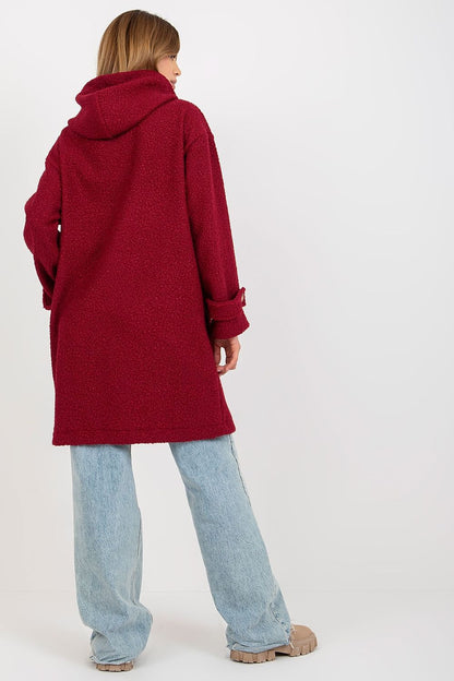 Back view of a woman elegantly dressed in a plush red coat with a hood, button closure, and loose denim, showcasing the luxurious and comfortable style.