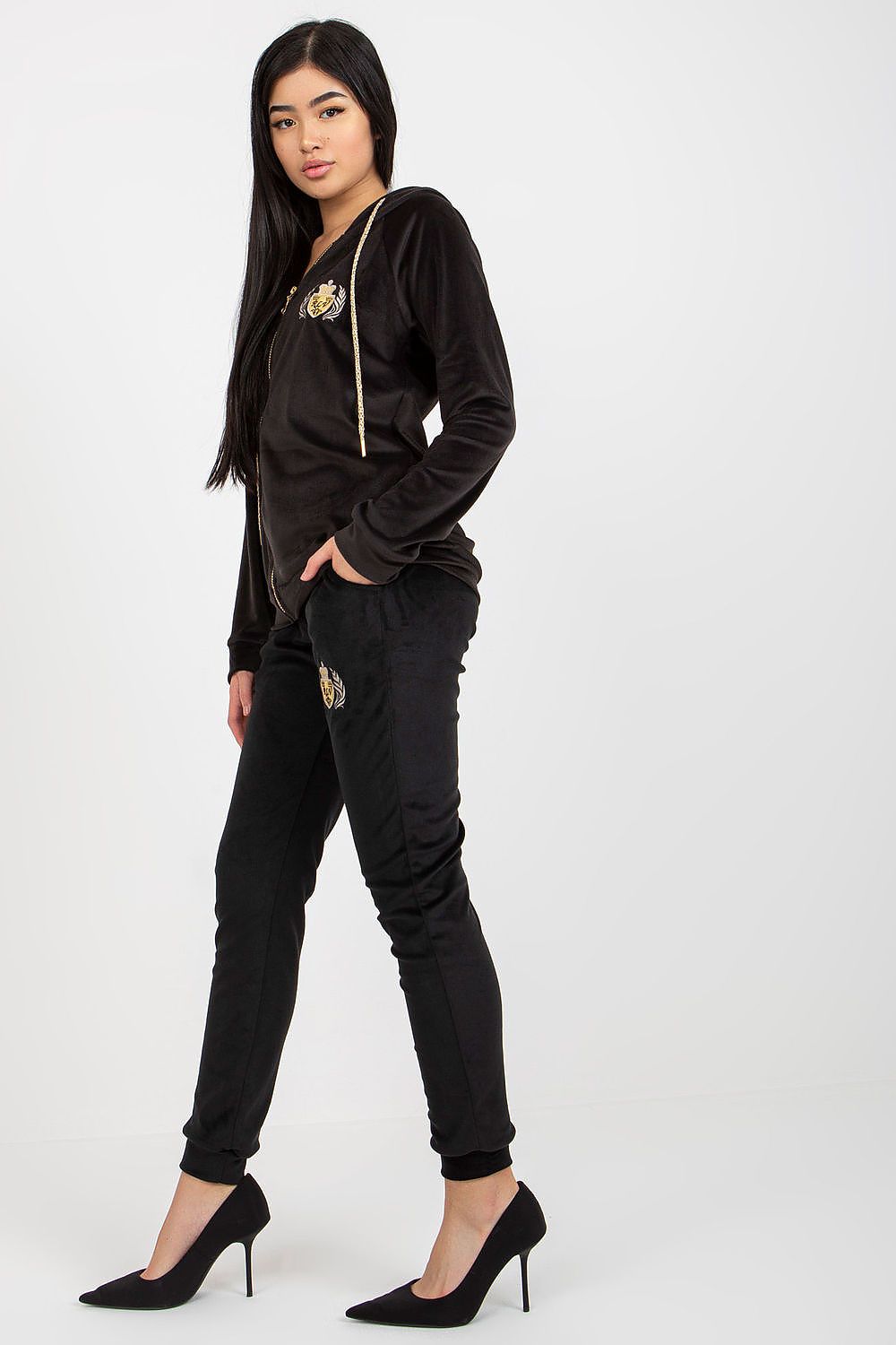 Chic women’s black velour set featuring a hoodie with an embroidered logo, partnered with sleek trousers, designed to offer a blend of elegance and casual flair for a fashionable look.