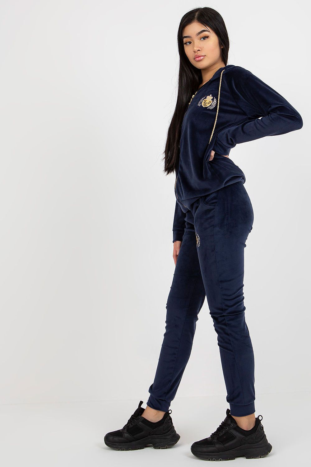 Stylish ladies' velour tracksuit in navy, featuring fashionable embroidery on both hoodie and pants, model displaying confidence.