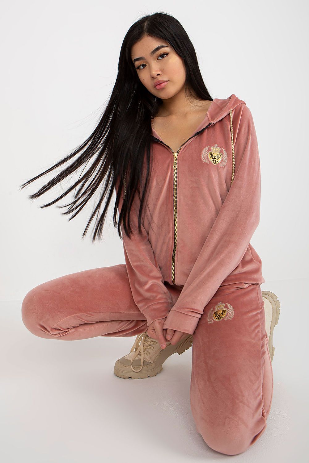 Chic velour tracksuit ensemble displayed in a sophisticated pose, showcasing the luxurious texture and rich blush tone, complemented by embroidered details.