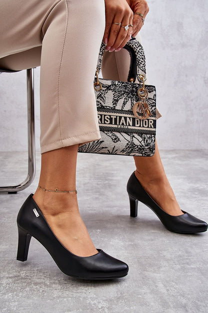 Sophisticated black block heel pumps paired with tailored trousers and a designer handbag, epitomising luxury fashion.