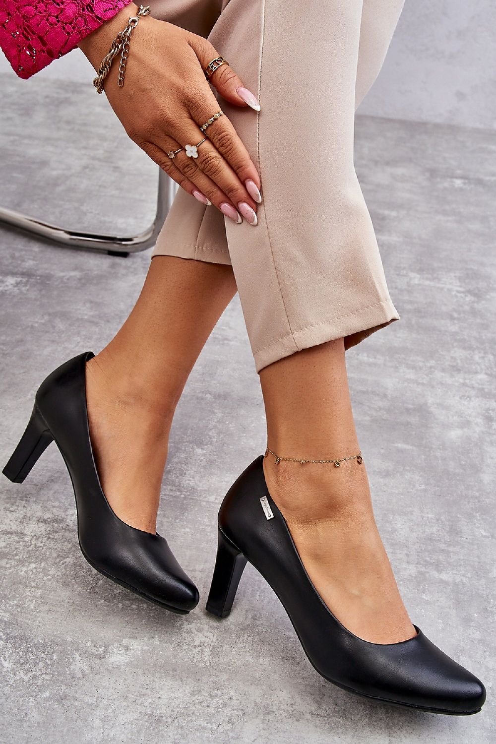 Stylish black block heel pumps highlighted alongside chic trousers and elegant accessories, presenting a sophisticated look.