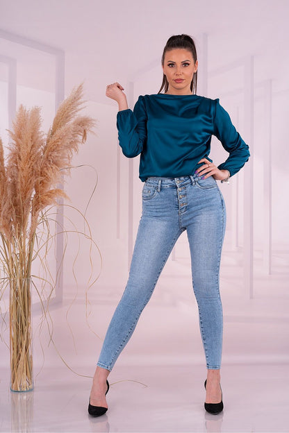 Elegant woman showcasing the Merribel Satin Long Sleeve Blouse in teal, paired with stylish high-waisted jeans, embodying sophistication.