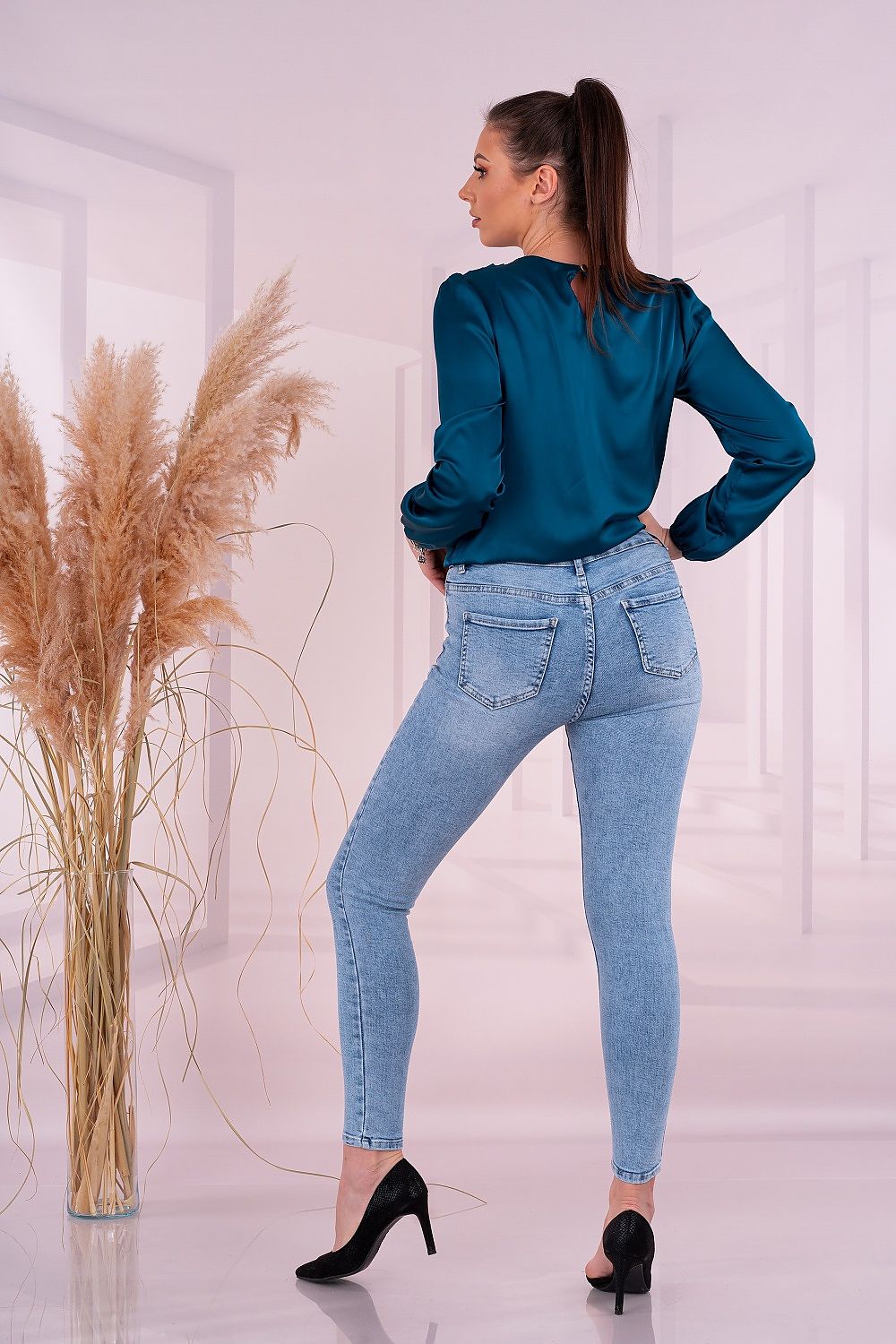 Back view of an elegant woman wearing the Merribel Satin Long Sleeve Blouse, highlighting the exquisite design and flattering fit in teal.