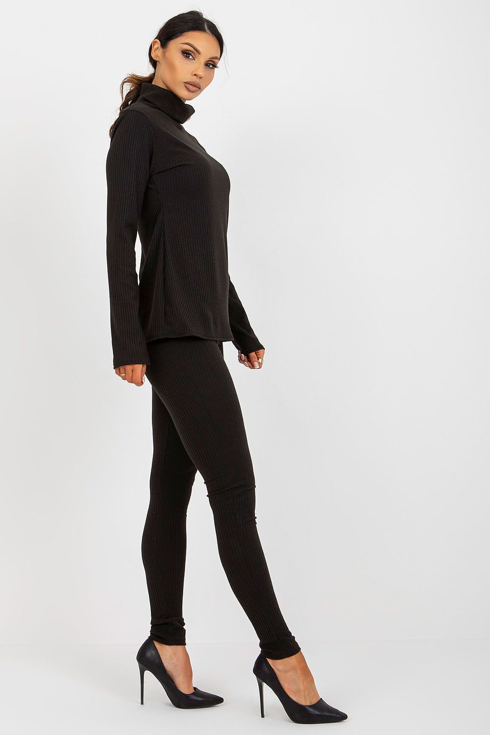 Chic side profile of a woman in a black ribbed turtleneck blouse and leggings by Lakerta, exuding luxury and contemporary fashion.