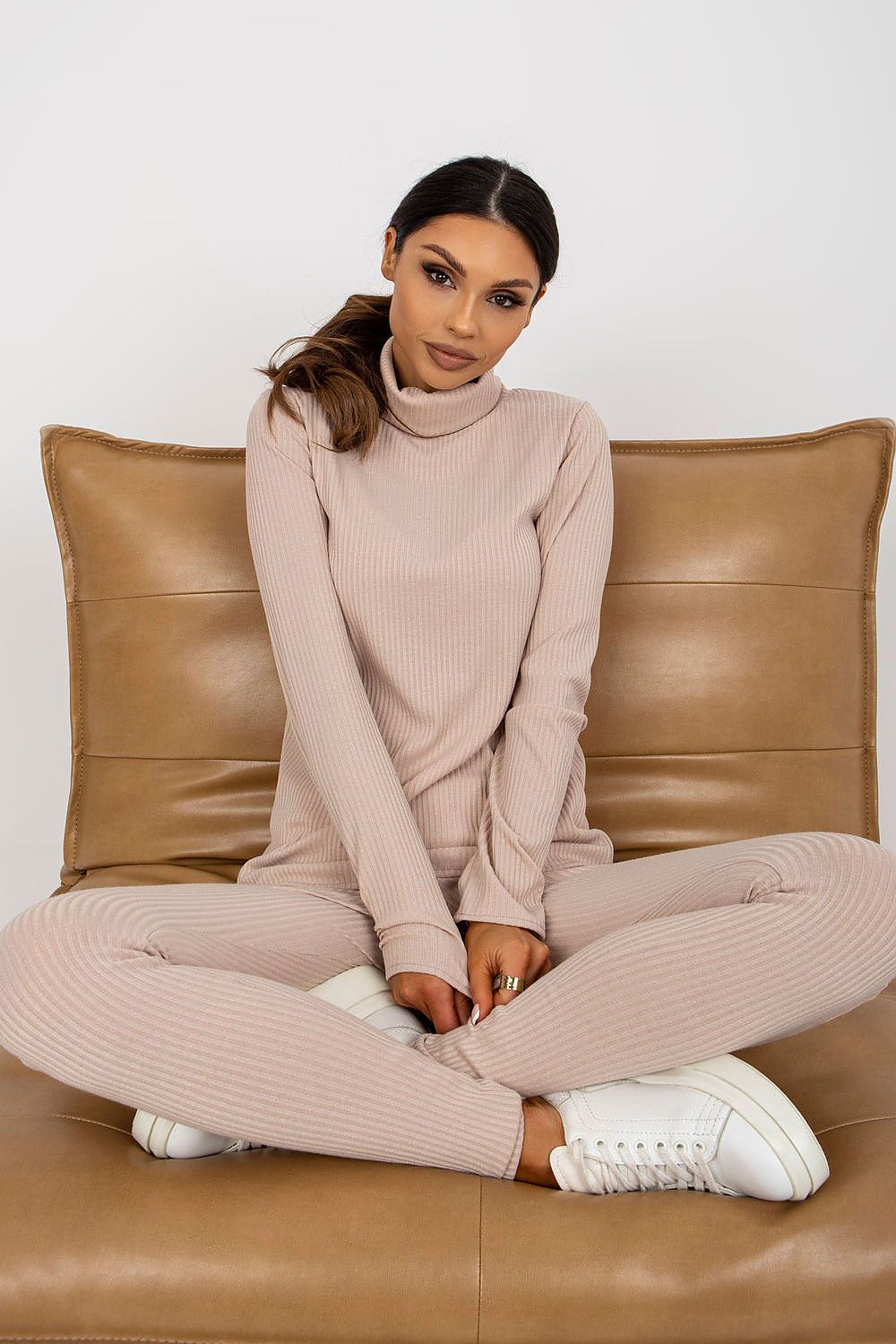 Luxury women's turtleneck blouse by Lakerta, featuring ribbed fabric, styled in a relaxed seated pose with a soft neutral background.