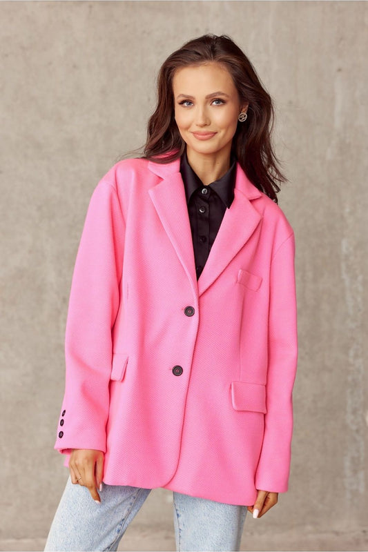 Roco Fashion's elegant voluminous pink jacket featuring a decorative collar and imitation pockets, styled effortlessly with a classic black shirt and light blue jeans against a textured grey backdrop.