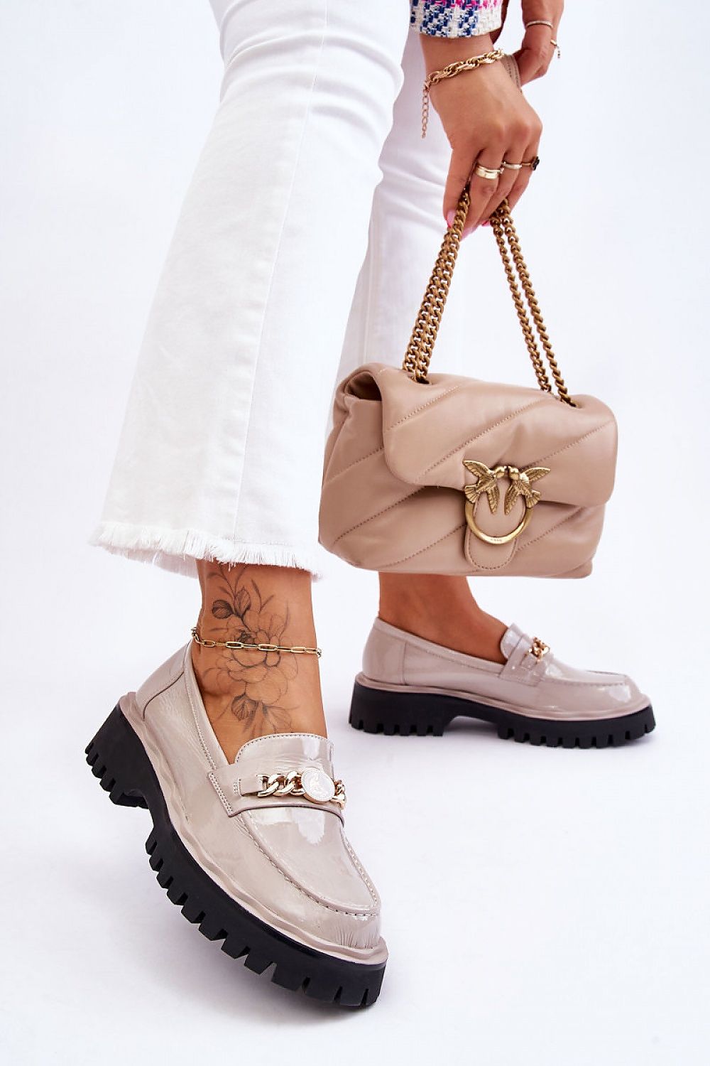 Stylish model showcasing Eco Leather Moccasin Shoes by Step in Style, featuring a decorative chain, paired with trendy white jeans and a chic handbag for an elegant look.