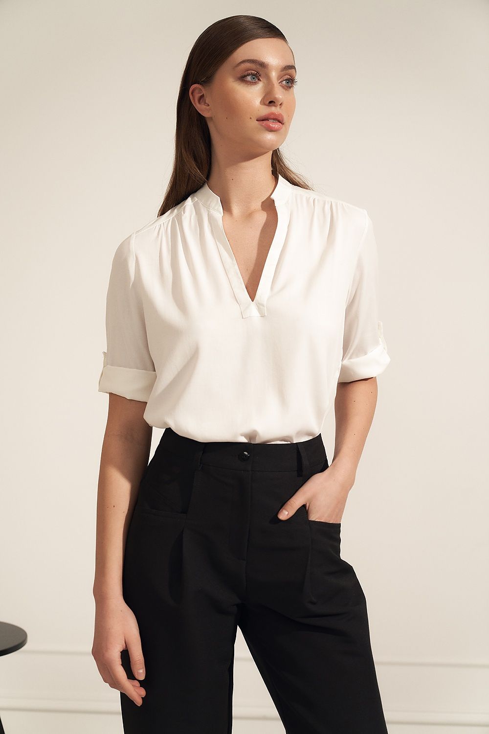 Elegant Nife high-quality viscose blouse featuring a unique neckline and rolled-up sleeves, paired with tailored black trousers, set against a stylish minimalist background.