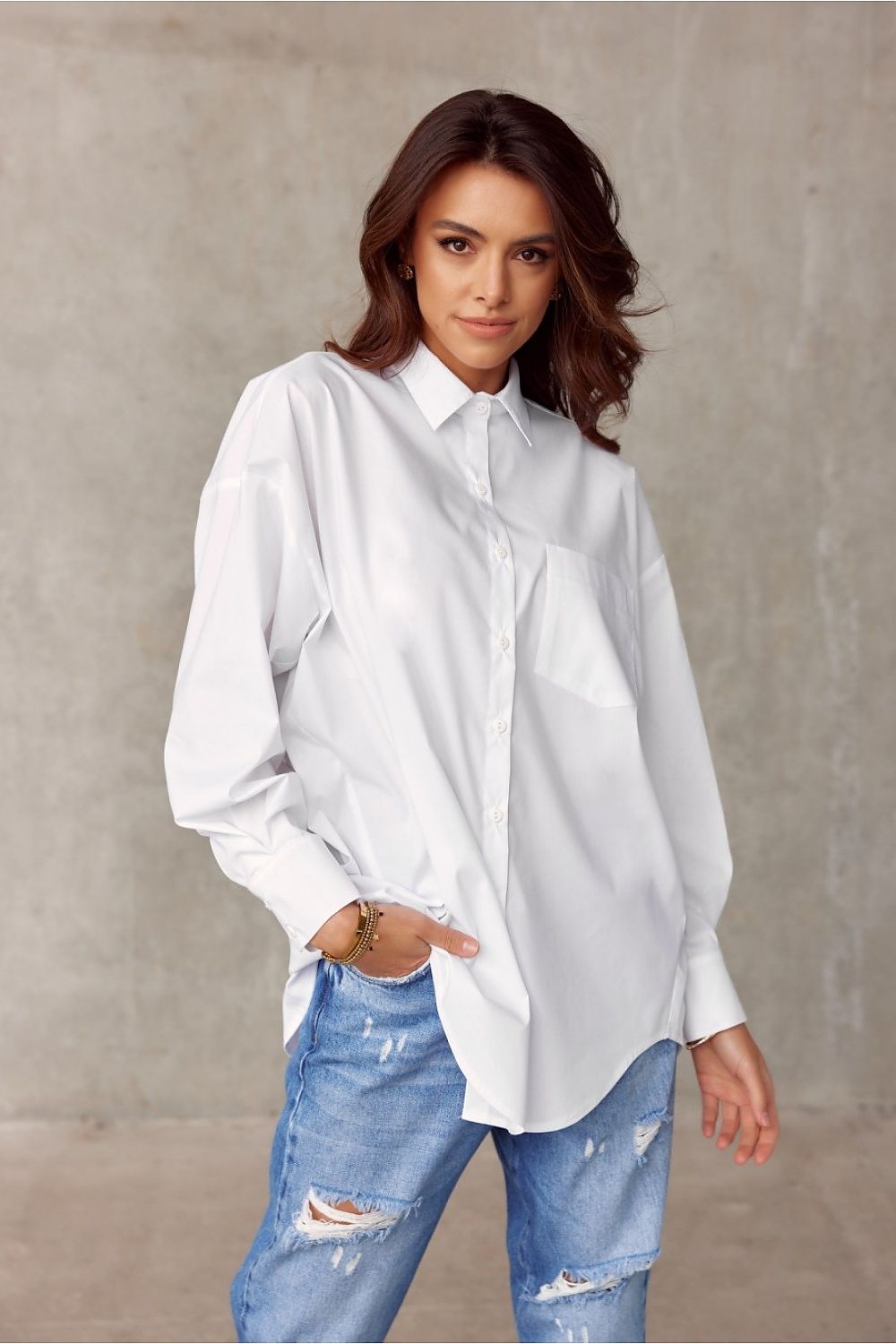 Timeless white oversized shirt from Roco Fashion, accented with a classic collar and front pocket, paired with distressed jeans for a stylish casual ensemble.