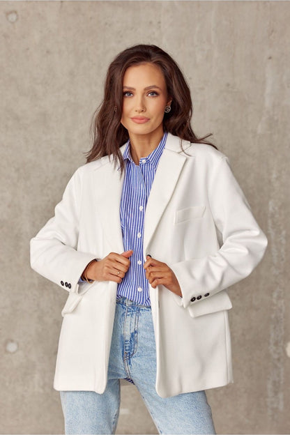 Close-up of a model in a fashionable white voluminous jacket from Roco Fashion, elegantly posed with a blue striped shirt and light denim, showcasing a blend of sophistication and casual elegance.