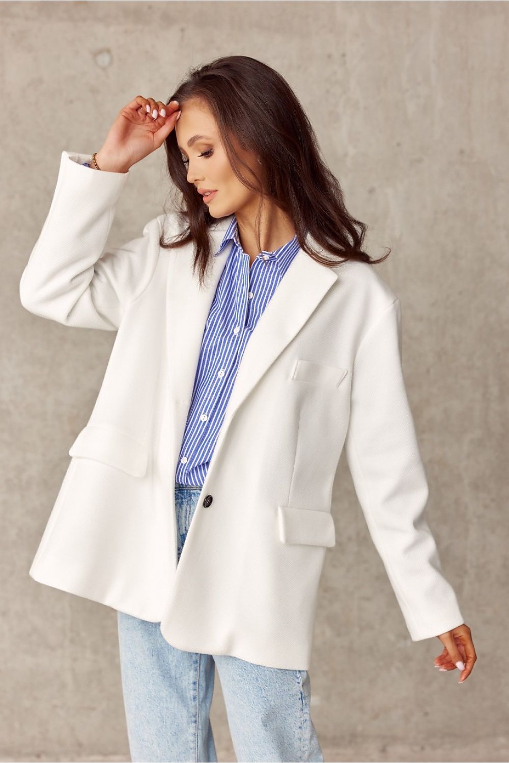 Chic voluminous jacket by Roco Fashion in white, featuring a decorative collar and imitation pockets, styled with a blue striped shirt and denim jeans, creating an elegant yet casual look.