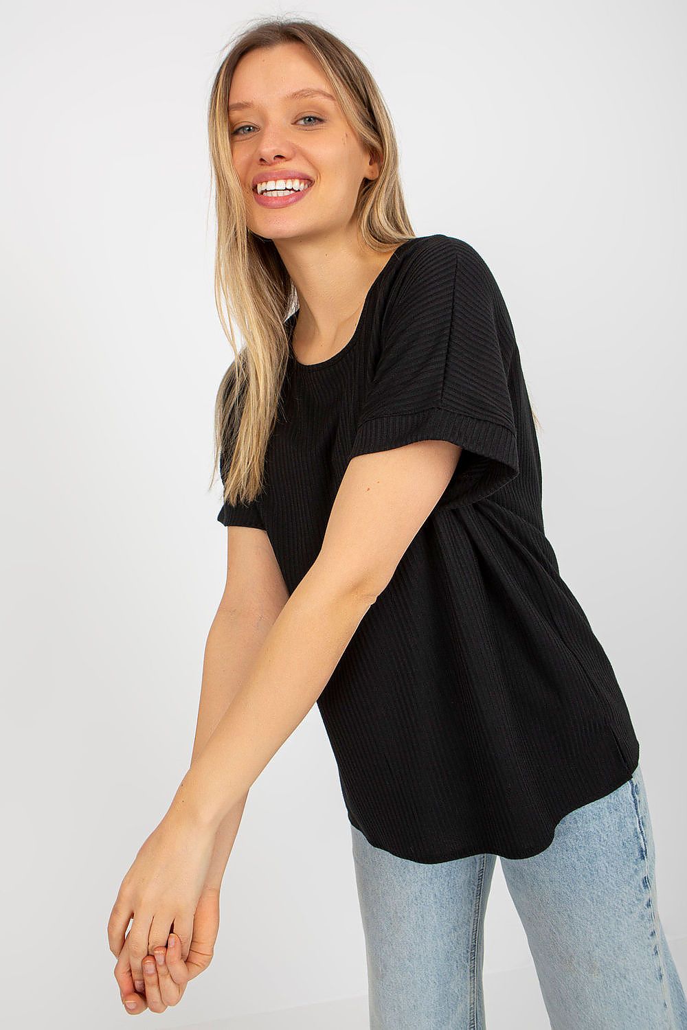 Model showcasing a luxury loose fit ribbed cotton blouse by Lakerta, accentuating the short sleeves and round neckline with a joyful expression.