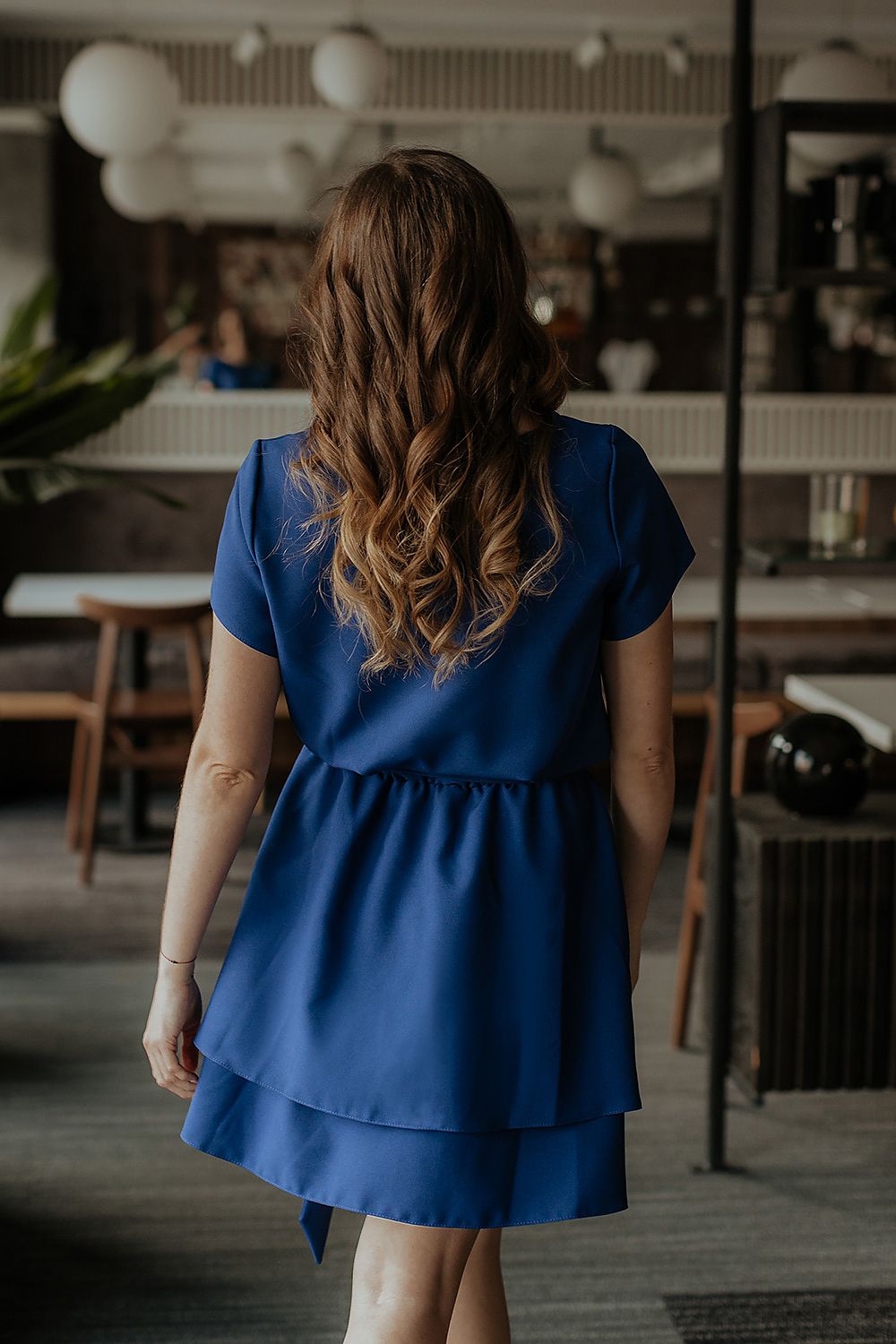 Model wearing the Tessita luxurious daydress, accentuating its flattering silhouette and double-layered flared bottom in a chic outdoor setting.