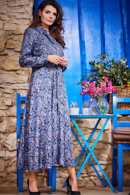 Chic model presenting the Awama maxi dress featuring a button-down design and paisley pattern, posed elegantly by a vibrantly painted wall.