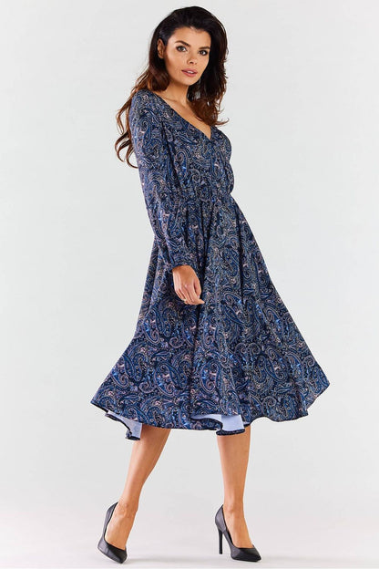Elegant midi dress by awama, featuring an envelope neckline, long sleeves, and a flowing flared hem, showcased by a model in a paisley print with high heels.