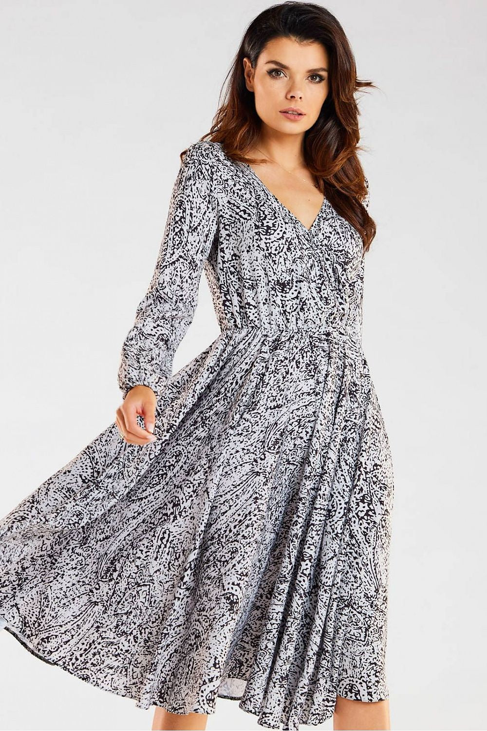 Stylish black and white patterned midi dress by awama, featuring an envelope neckline and long sleeves, model posed elegantly to showcase its flowing silhouette.