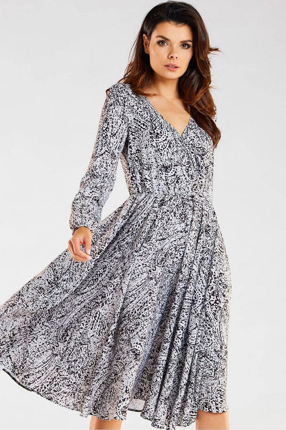 Stylish black and white patterned midi dress by awama, featuring an envelope neckline and long sleeves, model posed elegantly to showcase its flowing silhouette.