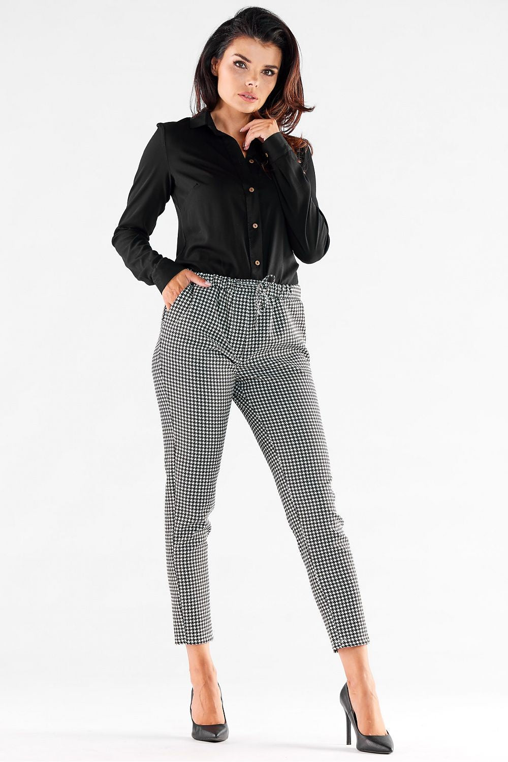Sophisticated women's casual trousers by Awama, showcasing a fashionable houndstooth design, complemented by an elasticized waistband and pockets, worn with a tailored black blouse.