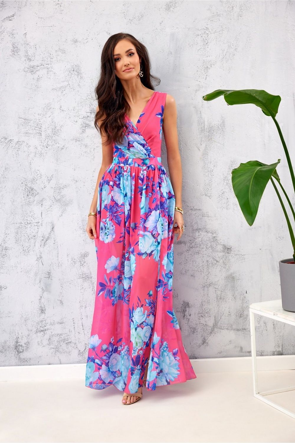 Elegant floral chiffon maxi dress in vibrant pink featuring a stunning blue floral pattern, designed by Roco Fashion. Showcased on a model against a textured backdrop, exuding grace and sophistication.
