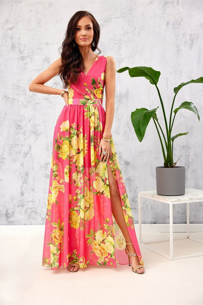 Luxurious floral chiffon maxi dress in striking pink adorned with yellow floral designs, highlighting a daring leg slit. Presented by Roco Fashion on a stylish model, radiating elegance and charm.