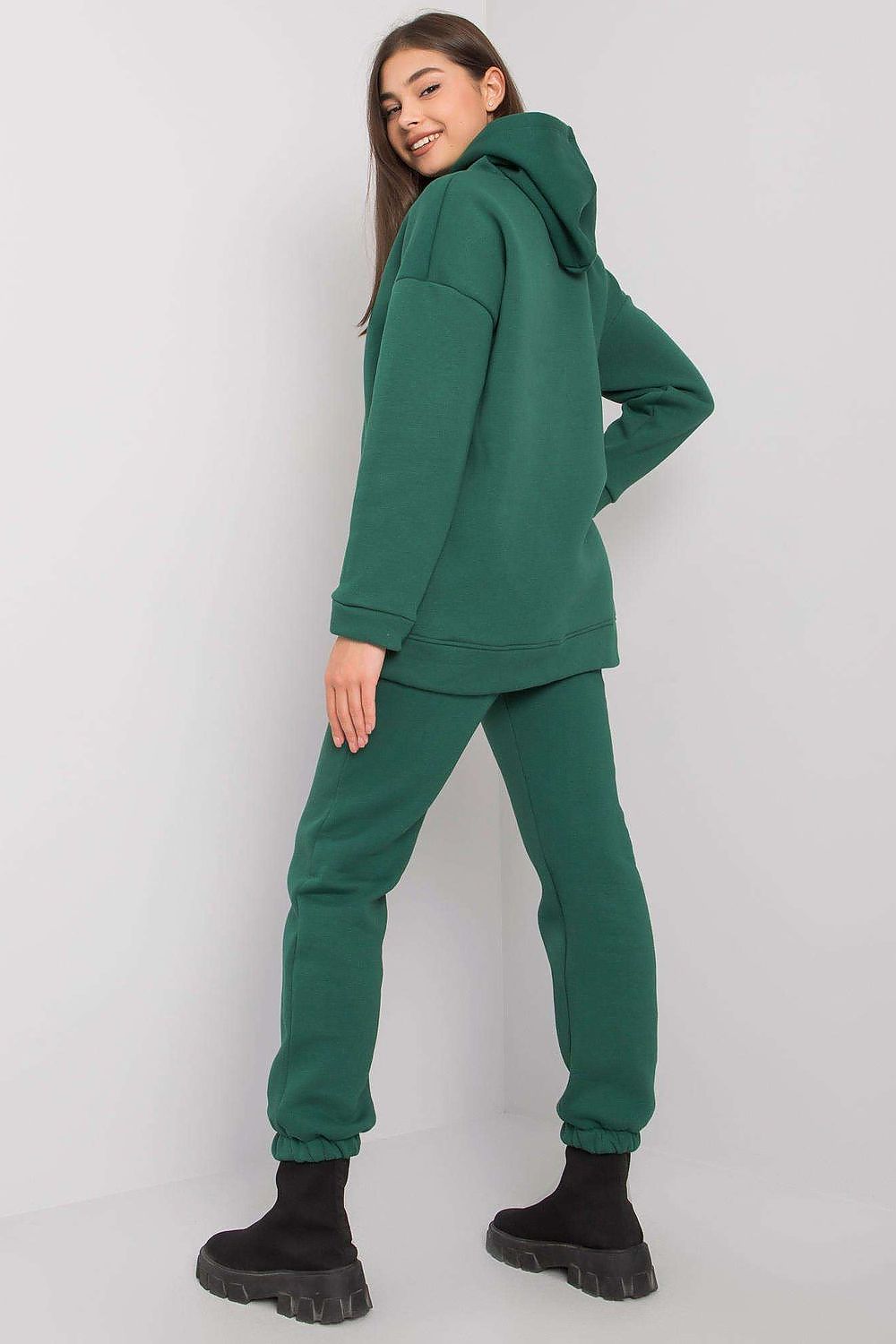 Back view of a fashionable woman in a BFG cotton-blend hoodie and matching pants, presenting a sophisticated look in deep green.
