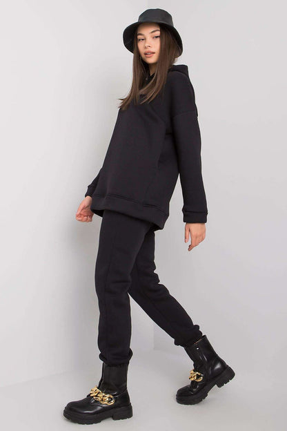 Side profile of a fashionable woman in a luxurious BFG black sweatshirt set with hood, styled with chic boots, highlighting modern elegance.