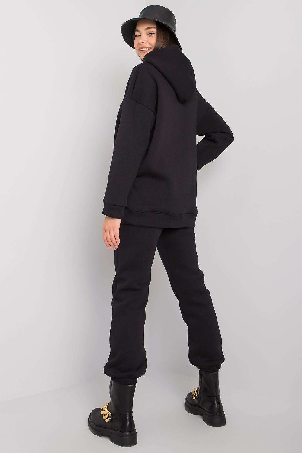 Stylish model showcasing a luxurious BFG cotton-blend sweatshirt set with hood and elastic waist pants in elegant black, paired with trendy boots and a chic bucket hat.