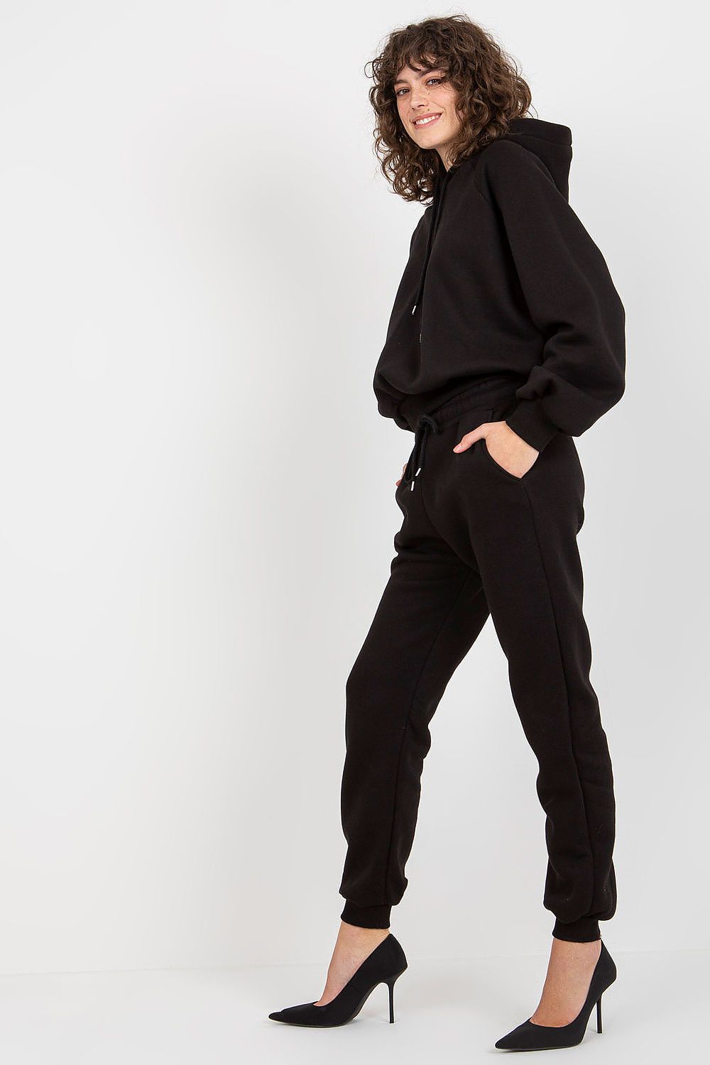 Ex Moda elegant black cotton-blend sweatshirt and pants set with hood, model showcasing stylish silhouette and high heels.