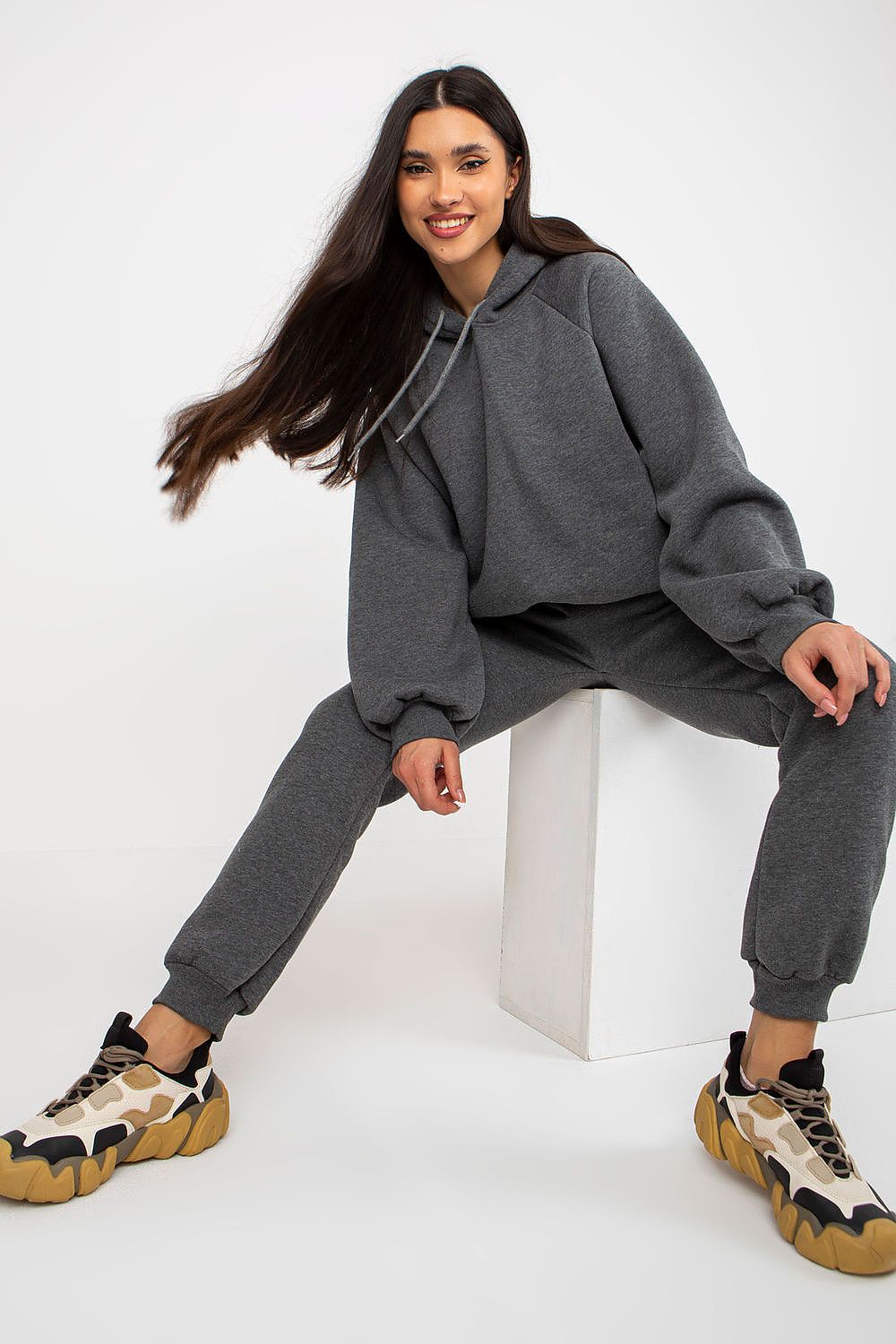 Contemporary model seated in the luxurious Ex Moda Premium Cotton-Blend Sweatshirt Set in grey, featuring a chic hood and comfortable fit for everyday elegance.