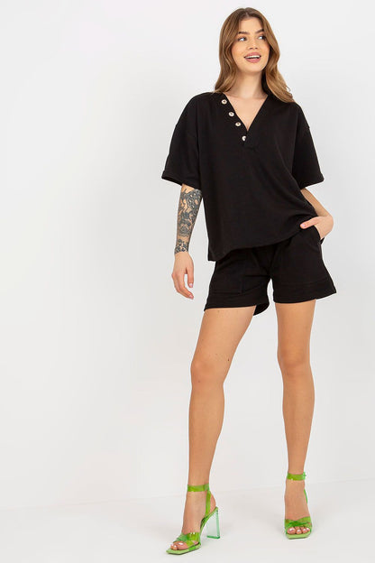 Model showcasing Ex Moda's luxurious cotton tracksuit set in black, featuring a heart neckline blouse paired with stylish shorts and green heels for a chic look.