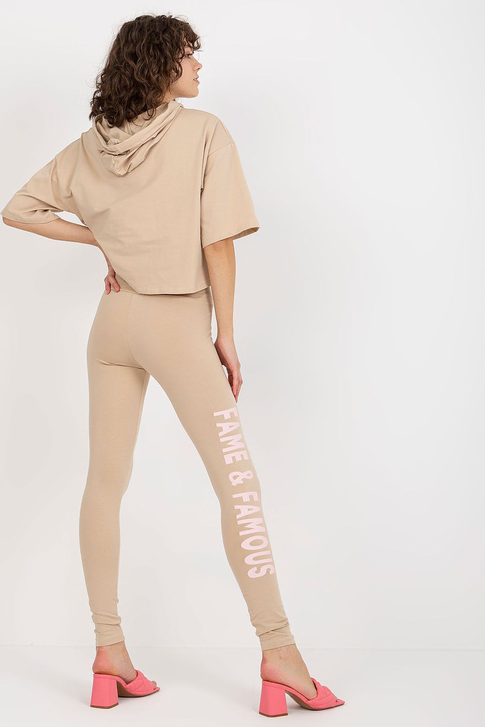 Chic back view of a woman in Ex Moda's cotton sweatshirt and leggings set, highlighting the hooded top and eye-catching decorative writing on the leggings.