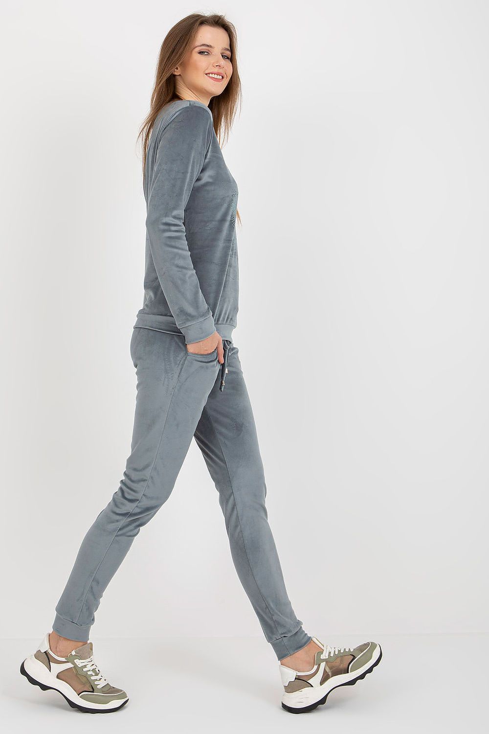 Profile view of a chic grey velour set by Relevance, paired with trendy sneakers, highlighting its modern design and delightful comfort.