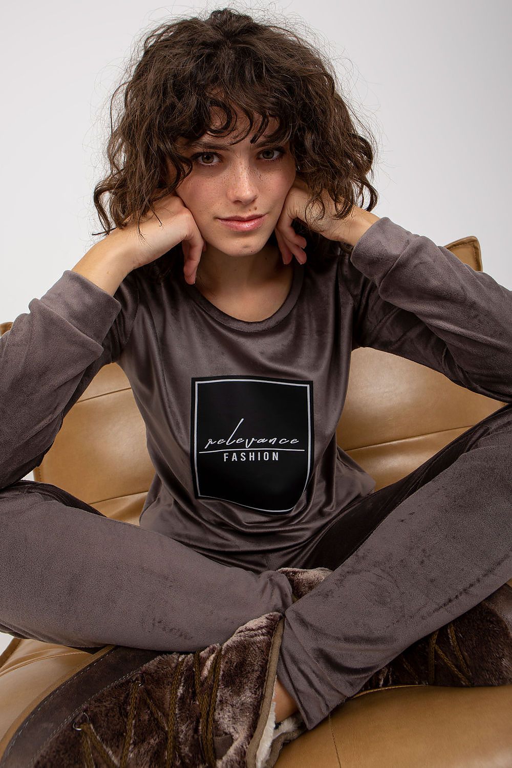 Close-up of a model in a sleek velour tracksuit set, with the stylish sweatshirt displaying 'relevance FASHION' inscription, exuding chic comfort by Relevance.