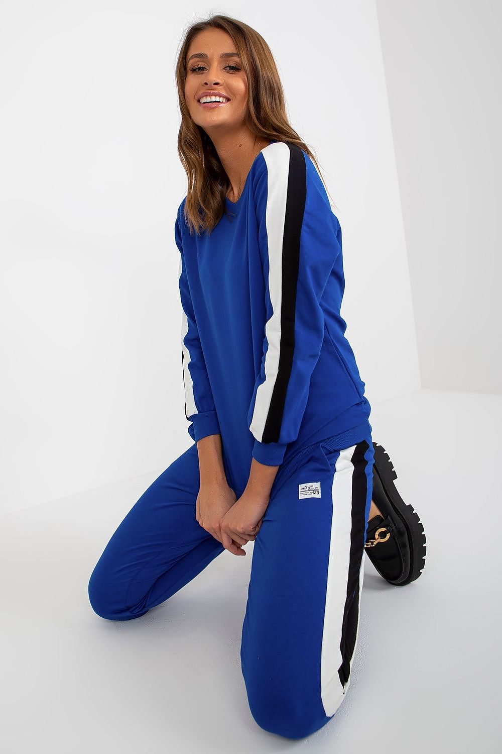 Chic and modern blue sweatshirt set by Relevance, accentuated with decorative stripes. Model in a playful pose, highlighting the stylish tie-waist pants and luxurious fabric blend.