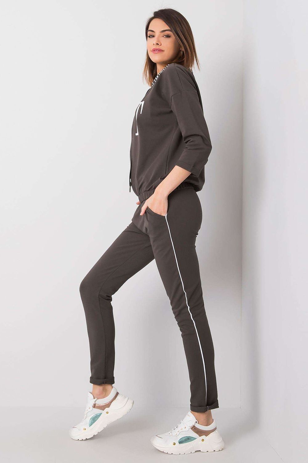 Side view of a fashionable woman wearing the Elegant Women's 2-Piece Tracksuit Set by Relevance, showcasing the contemporary design with white detailing on the long pants and a comfy sweatshirt with 3/4 sleeves.