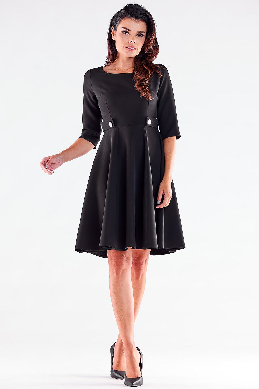 Front view of a graceful woman in a black Blushed Awama daydress, featuring stylish button accents and flowing skirt, paired with classic black heels.