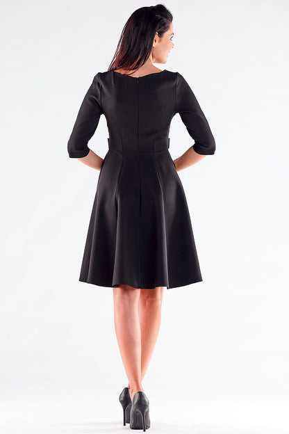 Back view of an elegant woman wearing a black Blushed Awama daydress, highlighting the fitted bodice and flowing skirt, finished with chic black pumps.