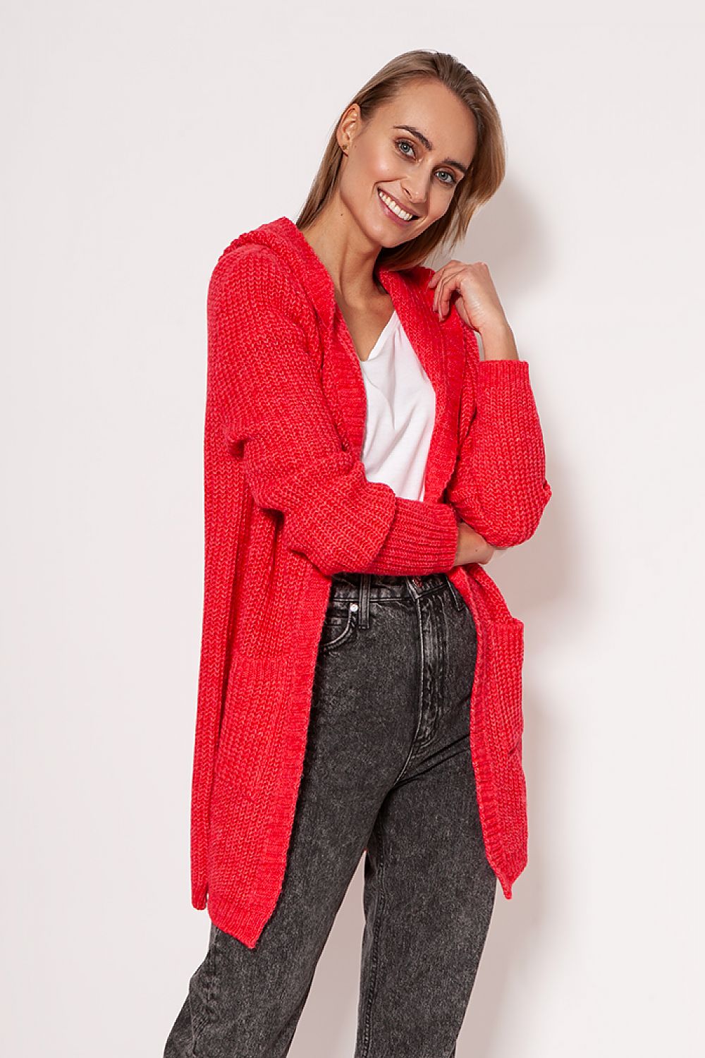 MKM luxurious soft cardigan coat in vibrant red, embodying a minimalist design with dropped shoulders and hip pockets, showcased by a smiling model in casual attire.